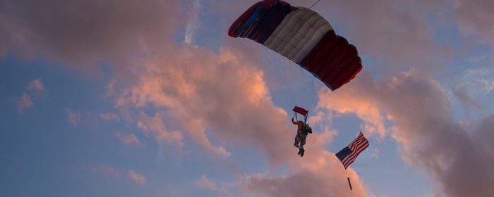 Skydiver parachutes at sunset.