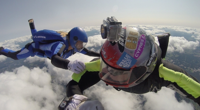 Two Professional Skydivers Floating Above the Clouds, One Wearing a Helmet Cameraa