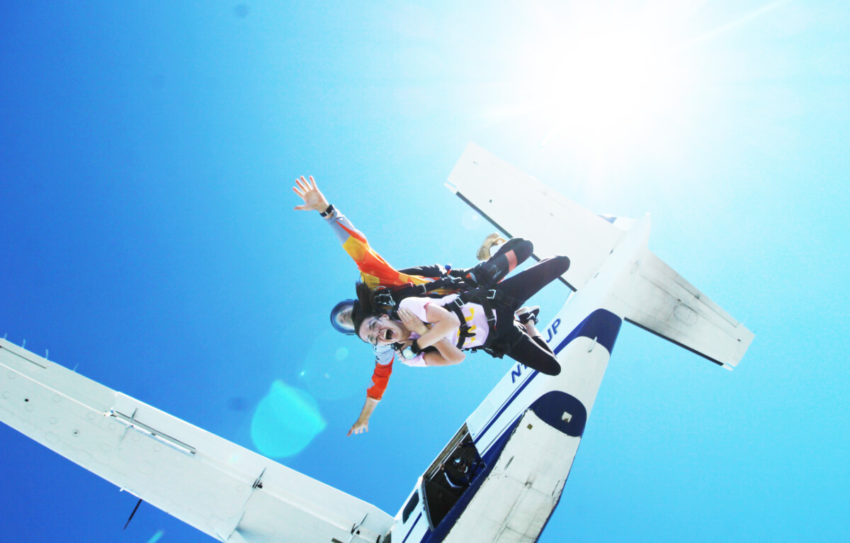 A tandem skydiving couple jump out a plane.