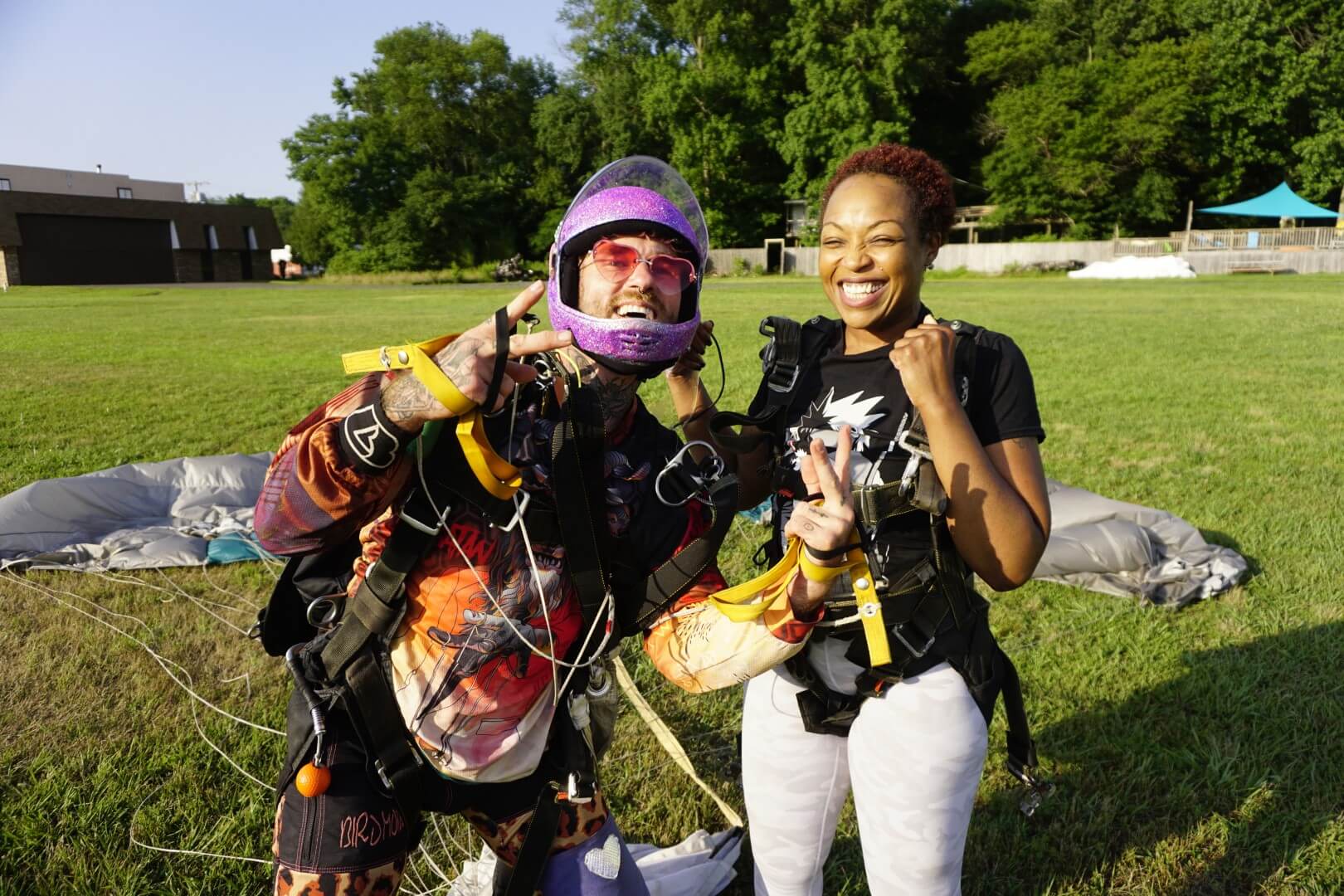 Two friends smiling on the ground after skydiving together.