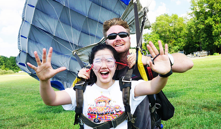 A girl with her instructor and parachute celebrating after skydiving at Skydive Cross Keys.
