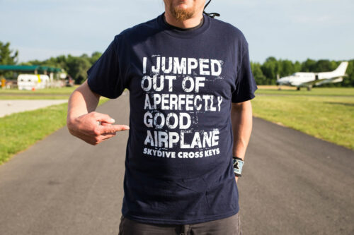 Skydiver on runway pointing to his skydiving tee shirt.