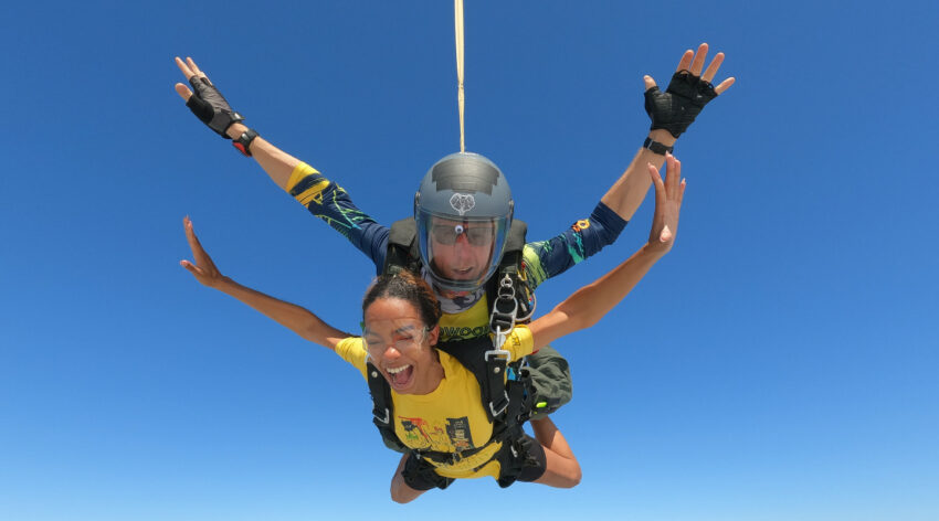 Tandem skydiver smiling during freefall.